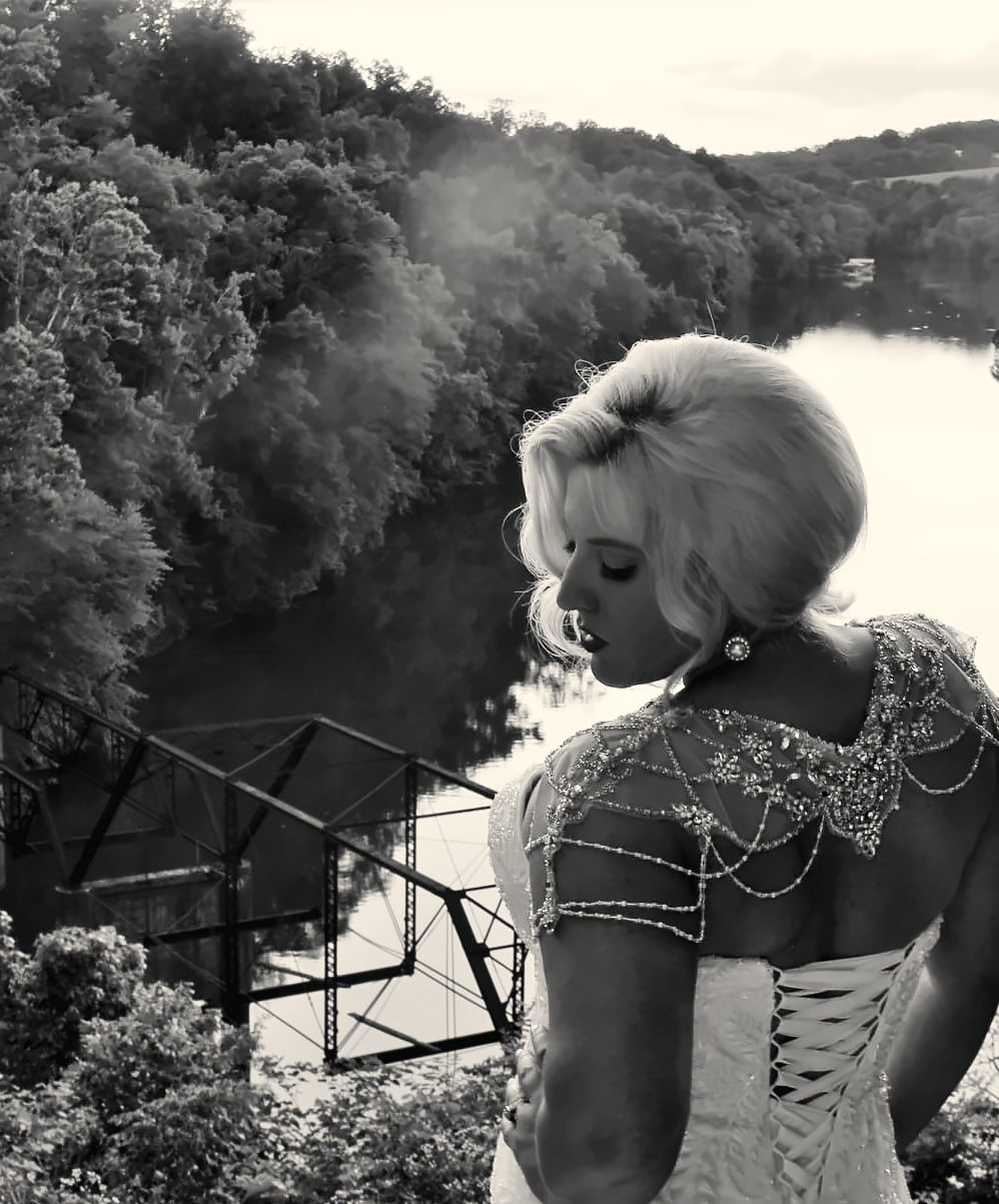 Bride with a sculpted vintage updo overlooking the river
